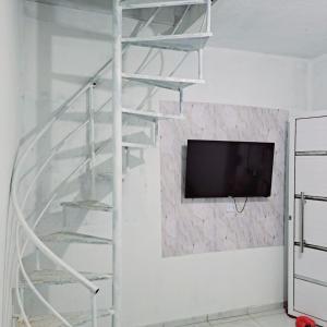 a metal spiral staircase with a tv on a wall at Casa de praia in Sirinhaém