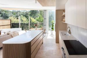 a kitchen with a counter and a living room at Beachfront Heated Pool 4Br Luxe Family Oasis Pets Welcome in Marcoola