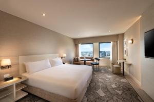 a hotel room with a large white bed and a desk at Hilton Darwin in Darwin