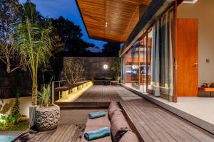 einen Unterhaltungsbereich im Freien mit einer Holzterrasse und einem Haus in der Unterkunft Domisili Villas Canggu Bali by Fays Hospitality in Canggu