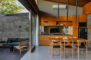 eine Küche und ein Esszimmer mit einem Holztisch und Stühlen in der Unterkunft Domisili Villas Canggu Bali by Fays Hospitality in Canggu