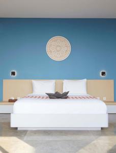 a blue bedroom with a white bed with a blue wall at Abian Kapas Beach House in Tabanan +45 photos