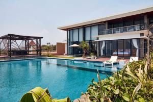 a house with a swimming pool in front of a building at Abian Kapas Beach House in Tabanan