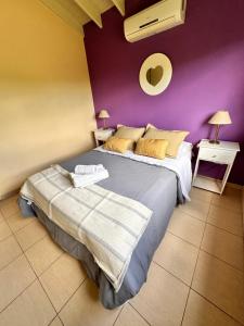 1 dormitorio con 1 cama grande y pared morada en Villa Bonita Cabañas en Merlo