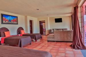 Habitación con 2 camas, sofá y TV. en Hotel Chocolate Suites, en Guanajuato