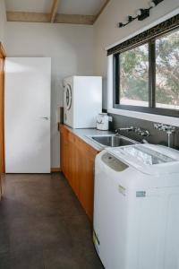 a kitchen with a white refrigerator and a sink at The PC Cottage in Port Campbell