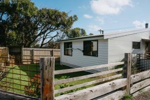 a white house with a fence next to it at The PC Cottage in Port Campbell