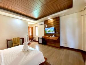 a room with a bed and a flat screen tv at The Nest El Nido Beach Resort in El Nido
