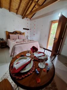 a room with a bed and a wooden table with plates at Chalés Cantinho do Céu in Monte Verde