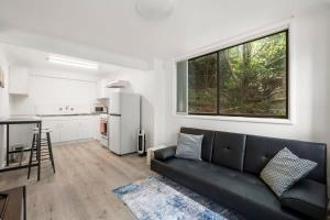 ein Wohnzimmer mit einem schwarzen Sofa und einer Küche in der Unterkunft Narrow Neck - Blissful hideaway in Katoomba