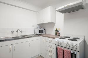 eine weiße Küche mit einem Herd und einer Mikrowelle in der Unterkunft Narrow Neck - Blissful hideaway in Katoomba