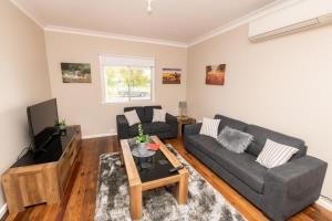 a living room with a couch and a tv at Kinross on Cox Sweet, Neat & Simple + Wifi in Orange