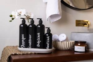 two black bottles sitting on a shelf in a bathroom at Blue Door Apartment 2 - CBD, Heritage, Ideal for Work in Orange