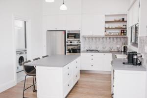 uma cozinha com armários brancos e um frigorífico branco em Dimby Cottage Beautifully Restored Heritage Home em Orange