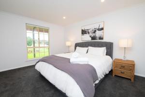 Un dormitorio blanco con una cama grande y una ventana en Darcy Brown House Modern Country Escape, en Orange