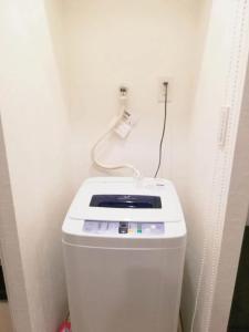a white toilet with a cord plugged into a wall at Shibuya Hana House in Tokyo