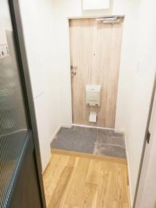 a small bathroom with a shower and a wooden floor at Shibuya Hana House in Tokyo
