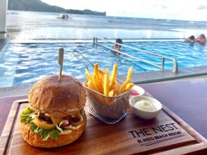 a sandwich and french fries on a tray next to a swimming pool at The Nest El Nido Beach Resort in El Nido