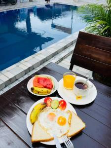 um pequeno-almoço com ovos e frutas em pratos junto a uma piscina em Vang Vieng Global Hostel em Vang Vieng