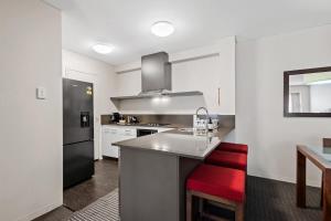 a kitchen with a counter and a red chair in it at Cosy Apartment in the Heart of Perth CBD in Perth +23 photos