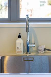 a sink with a bottle of soap sitting next to it at Charming 3 Bedroom Home Near Christchurch City in Christchurch