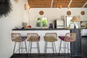 a kitchen with a counter with three bar stools at Villa Moana Poe Uluwatu in Uluwatu