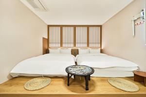 two twin beds in a room with a table at Gyeongju Hotel Gonggan in Gyeongju