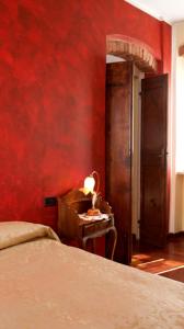 a bedroom with a red wall with a bed and a table at Vecchia Locanda in Sarzana