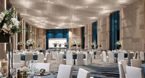 万隆Hotel Indigo Bandung Dago Pakar by IHG的有桌子、白色椅子和舞台的宴会厅