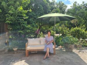 a woman sitting on a bench under an umbrella at Katie's homestay in Ðông Mỹ (2)