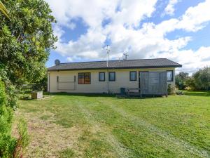 a small white house with a large yard at Arawai - Waimarama Holiday Home in Waimarama