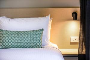 Una cama con una almohada verde y blanca. en Nightcap at Marine Hotel Cardwell, en Cardwell