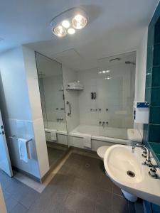 a bathroom with a sink and a tub and a toilet at South Yarra Central Apartment Hotel in Melbourne