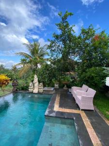 德格拉朗Dukuh Village Villas & Art的游泳池旁带紫色沙发的游泳池