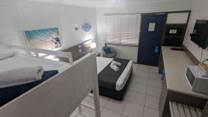 Moffat Beach Motel Caloundra في كالوندرا: غرفة صغيرة بها سرير وحمام