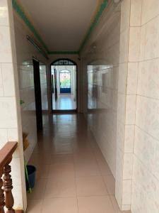 a hallway with white tile walls and an open door at Ditar Guest House D in Battambang