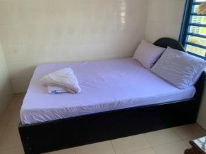 uma cama com lençóis brancos e almofadas em Ditar Guest House D em Battambang