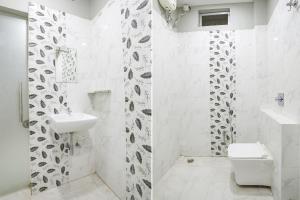 a white bathroom with a sink and a toilet at FabHotel The Bell in Bhilai