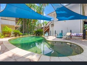 - une piscine en face d'une maison avec un parasol bleu dans l'établissement 29b Casa DeGregory, In the heart of Parap, à Paraparap