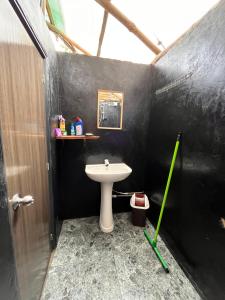 een badkamer met een witte wastafel en een zwarte muur bij Backpackers Hostel in Ella