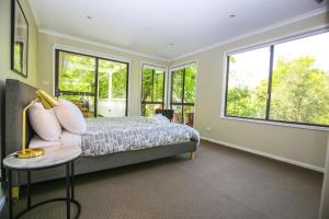 a bedroom with a bed with a chair and windows at Alderwood in Bright