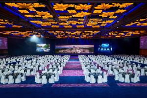 une salle de banquet avec des chaises blanches et une scène dans l'établissement Resorts World Sentosa - Crockfords Tower, à Singapour