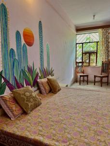 una camera da letto con un letto decorato con un murale di cactus di JWALA JAIPUR a Jaipur