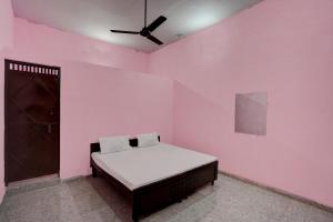 um quarto com uma cama numa parede cor-de-rosa em OYO Hotel star palace em Noida