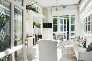 a living room with white furniture and windows at Grand Hotel Des Bains in Riccione