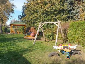 a wooden swing set in the grass with a toy at Störtebeker Comfortable holiday residence in Middelhagen