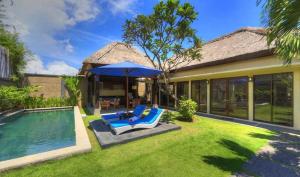 een achtertuin met een zwembad en stoelen en een parasol bij Bali Rich Villas in Seminyak