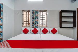una camera da letto con un grande letto bianco con cuscini rossi di OYO Pothini Palace a Palni