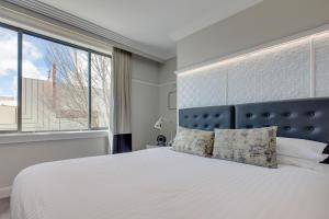 a bedroom with a white bed and a large window at Mountain Retreat, Steps from Train Station in Katoomba