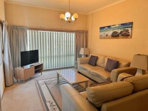 a living room with a couch and a tv at Unit 5 Kimberley Lodge in Merimbula